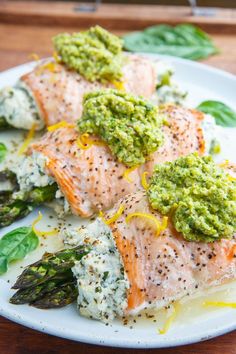 salmon with pesto sauce and asparagus on a white plate, ready to be eaten