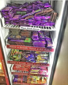 a refrigerator filled with lots of different types of candy and chocolate bars on shelves next to each other