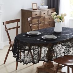 a dining room table with two chairs and a black table cloth on top of it