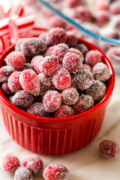 a red bowl filled with powdered sugar covered cranberries on top of a table