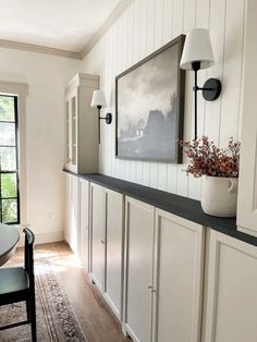 a dining room with white walls and wood flooring on the far wall is a framed painting