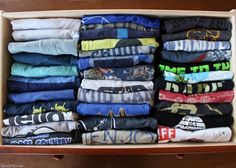 an open cardboard box filled with lots of folded shirts and t - shirts on top of each other