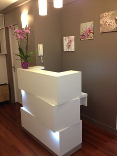 a white reception table with flowers on top and lights above it in a room that has wood floors