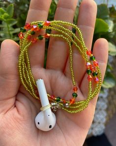 a hand holding an earbud with beads on it and a cord in the middle