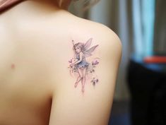 the back of a woman's shoulder with a fairy tattoo on her left shoulder