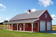 a large red barn with a white roof and two garage doors on the side of it