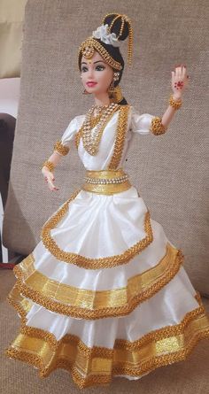 a figurine that is wearing a white and gold dress