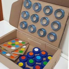 an open cardboard box filled with lots of different colored buttons and magnets on top of a table