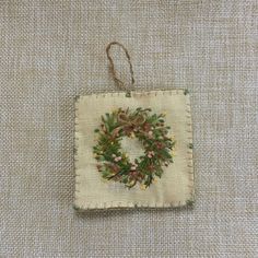 a small square ornament with a wreath on it's front and side