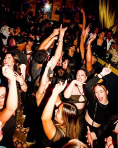 a group of people standing around each other at a party with their hands in the air