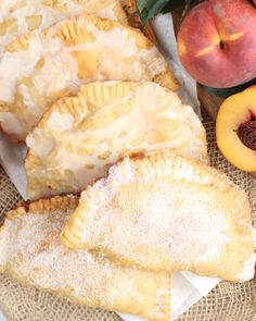 peach pastries with powdered sugar sit on a table next to fresh peaches