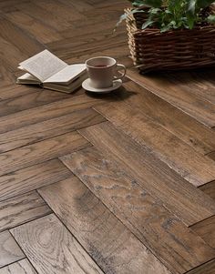 a coffee cup, book and plant on a wood flooring design that looks like herringbones