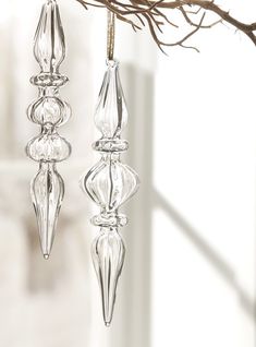 two clear glass candlesticks hanging from a twig on a branch in front of a window