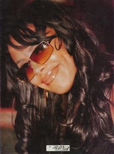 a woman wearing sunglasses and smiling for the camera