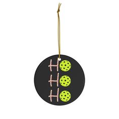 a black ornament with green and pink polka dots hanging from a gold hook