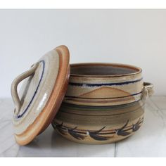 two ceramic bowls with lids sitting on a table