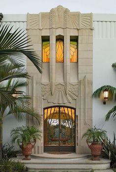 an entrance to a building with potted plants and palm trees