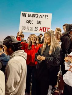 a group of people standing around each other with signs in front of them that read the weather may be cool but ge is hot