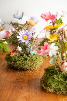 three vases filled with flowers on top of a wooden table next to each other