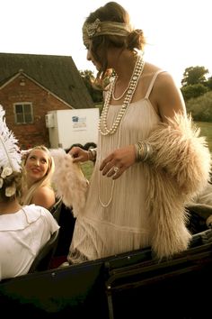 two women in native garb standing next to each other and one woman holding a feathered purse