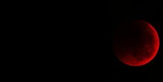 a red moon is seen in the dark sky