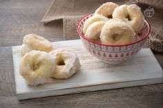 doughnuts sit in a bowl on a cutting board