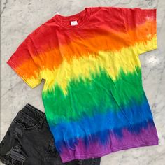 a rainbow colored t - shirt and black denim shorts on a marble counter with white background