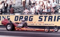 a drag car is going down the track in front of a crowd