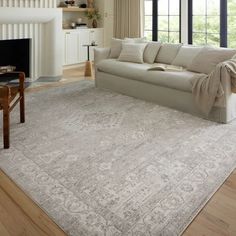 a living room with a couch, chair and rug on the floor in front of a fireplace