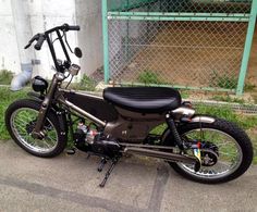 the motorcycle is parked on the side of the road by the fence and gated in area