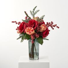 a vase filled with red flowers and greenery