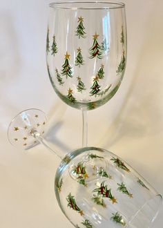 two wine glasses decorated with christmas trees and gold stars on the bottom one is empty