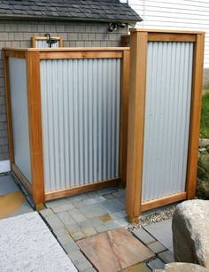 two tall wooden gates sitting next to each other on top of a stone floored walkway