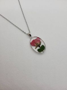 The charm for the necklace is made from epoxy resin with a real pressed flower inside.  The flower is a rose bud from Idaho.  It has a metal base around the charm, which matches the chain.  It is very lightweight and perfect for any occasion, whether formal or casual. Rose Flower Shaped Jewelry With Pressed Flowers, Rose Flower Jewelry With Pressed Flowers, Rose Bud, Wing Earrings, Pressed Flower, Real Flowers, A Rose, Rose Buds, Pressed Flowers