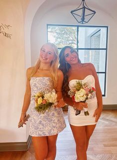 two beautiful young women standing next to each other holding bouquets in their hands and smiling at the camera