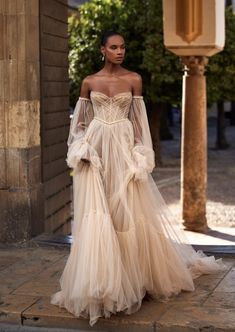 a woman in an off - the - shoulder dress is standing outside