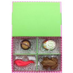 an open box with four different types of cookies in it on a checkered table cloth