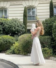 a woman in a white dress holding a baby