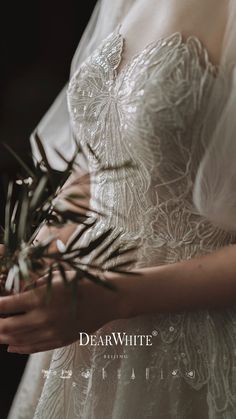 a woman wearing a wedding dress holding a plant in her hand and looking at the camera