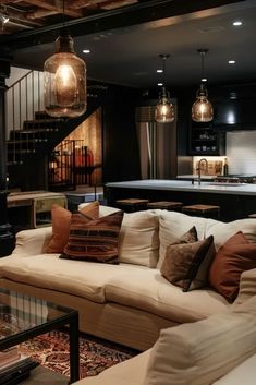 a living room filled with lots of furniture next to a stair case and table in front of a kitchen