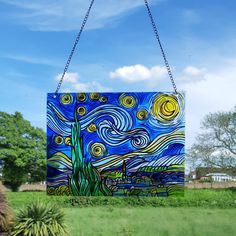 a painting hanging from a chain in the grass