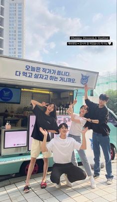 four people standing in front of a food truck with their arms up and one person holding an ice cream cone