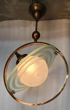 a light fixture with a glass globe on it's side and a metal ring hanging from the ceiling