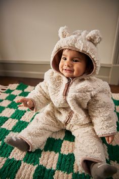 Off-white fleece suit for babies and toddlers by Molo of Denmark. The fleece suit has a zip, a hood with sewn-on small teddy bear ears, and with beige trim. The fleece suit is insulated and can therefore be used on its own or as an extra layer under the snowsuit on the coldest days. Foldover covers for hands and feet.Take a look at the rest of our Molo Collection here Details: 100% Recycled Polyester from plastic bottles Foldover covers for hands and feet Gentle wash cold, close zippers before wash, inside out. Do not iron. Tumble dry, low. Do not bleach. Do not dry clean. This Molo product is made from 100% recycled polyester, produced from reused plastic bottles and other residual waste. The production of recycled polyester requires far fewer resources and emits less CO2. Winter Sandals, Small Teddy Bears, Baby Sunglasses, Diaper Bag Accessories, Jumpsuit White, Winter Suit, Native Shoes, Leggings And Socks, White Fleece