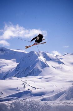 a person on skis jumping in the air with mountains in the backgroud