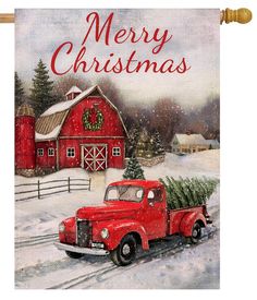 an old red truck with a christmas tree on the back in front of a barn