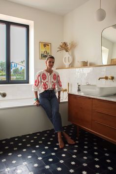 a woman sitting on the edge of a bathtub in a bathroom next to a sink