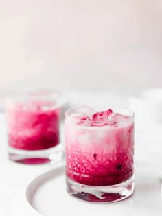 two glasses filled with red liquid on top of a white plate