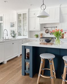 two stools sit in front of an island with white cabinets and blue countertops