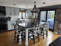 a kitchen with white cabinets, black counter tops and wooden floors is pictured in this image